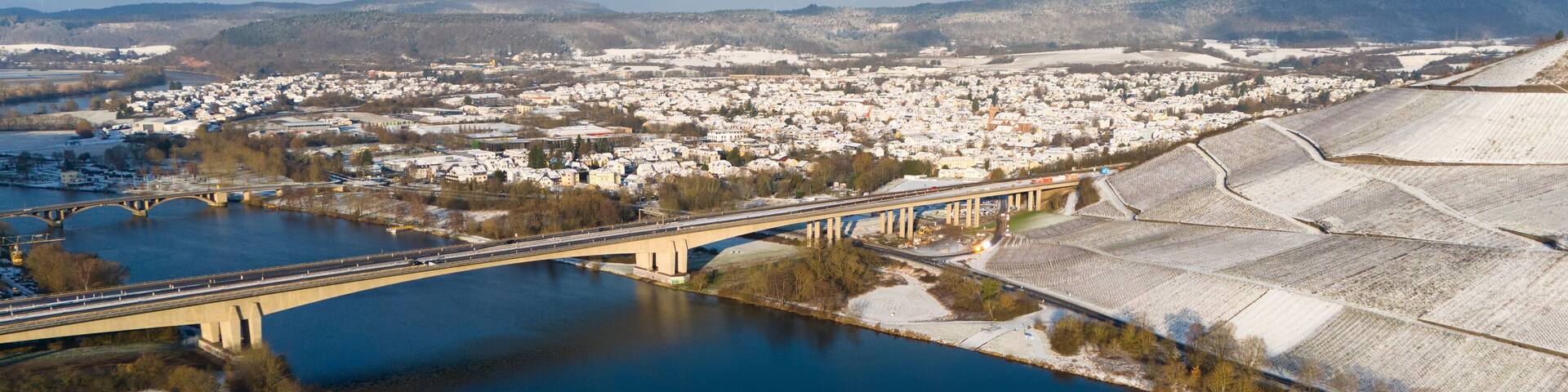 Snow covered Moselle valley, vineyard and Mosel river, Viaduct Longuich bridge of highway crossing near Trier, aerial view, winter season with frost in Germany