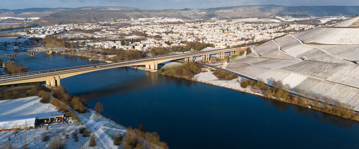 A bridge over a river, a town, and snow-covered fields.