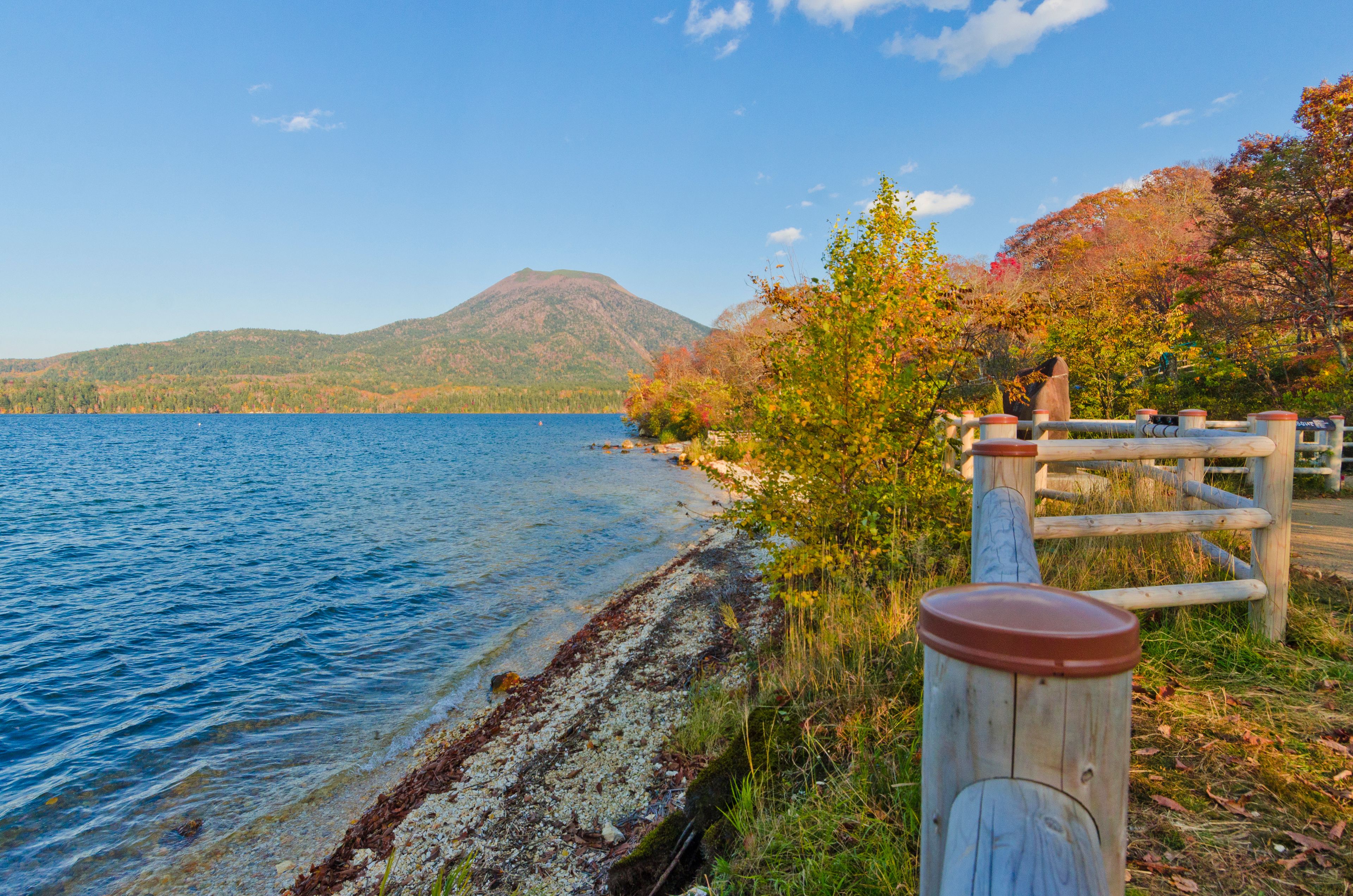 A lake with a wooden fence and a mountain in the background.