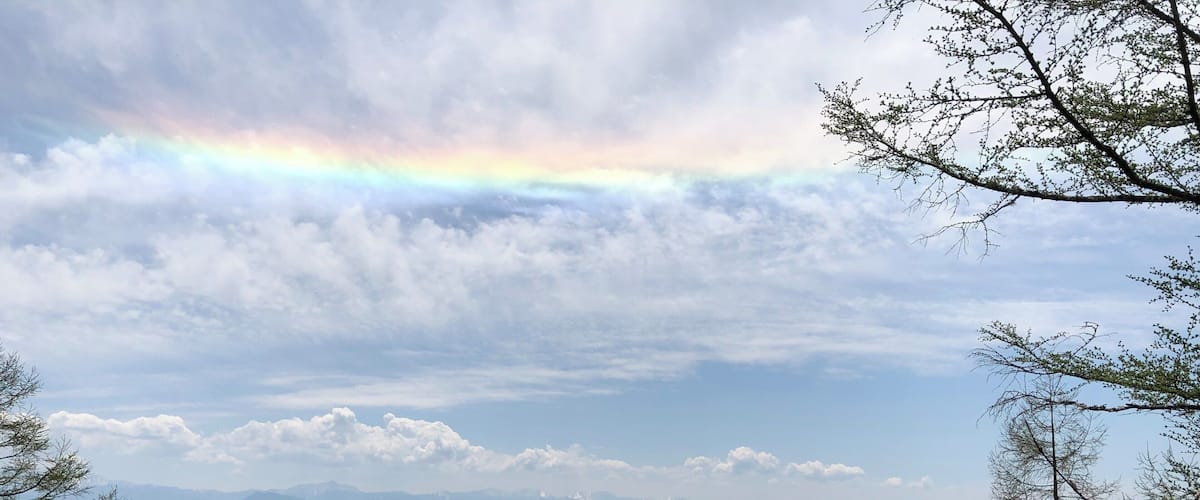 A mountain landscape with a rainbow, dense forests, and a distant city.