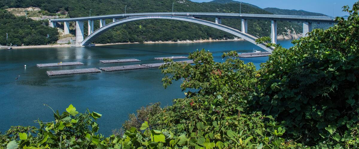 A bridge over a river with mountains in the background.