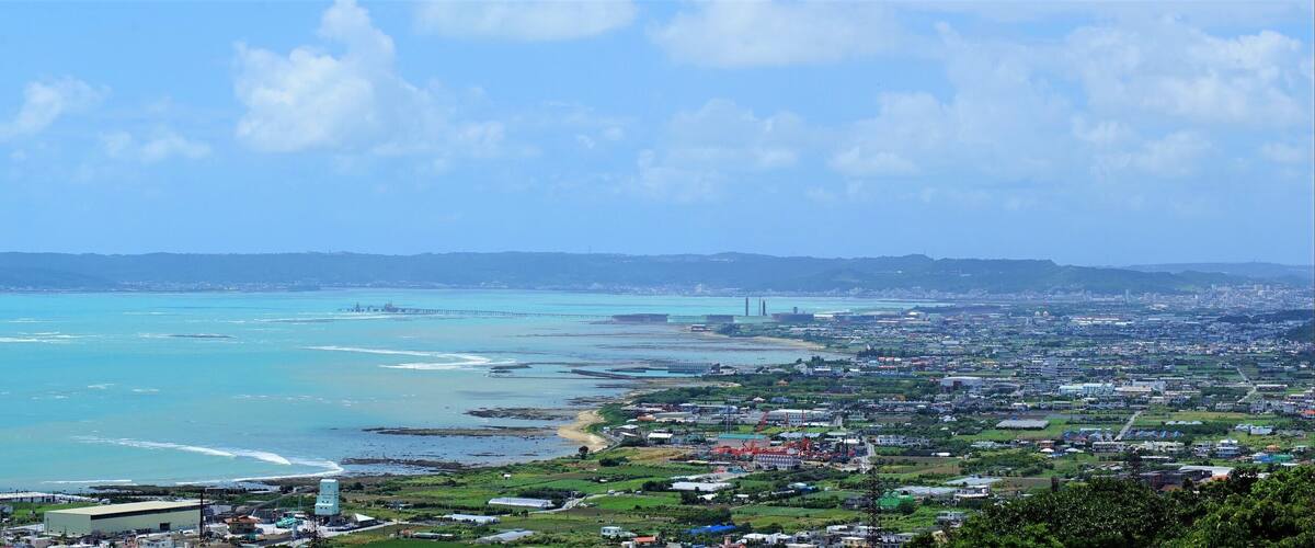A coastal city with a large bay, a bridge, and distant hills.
