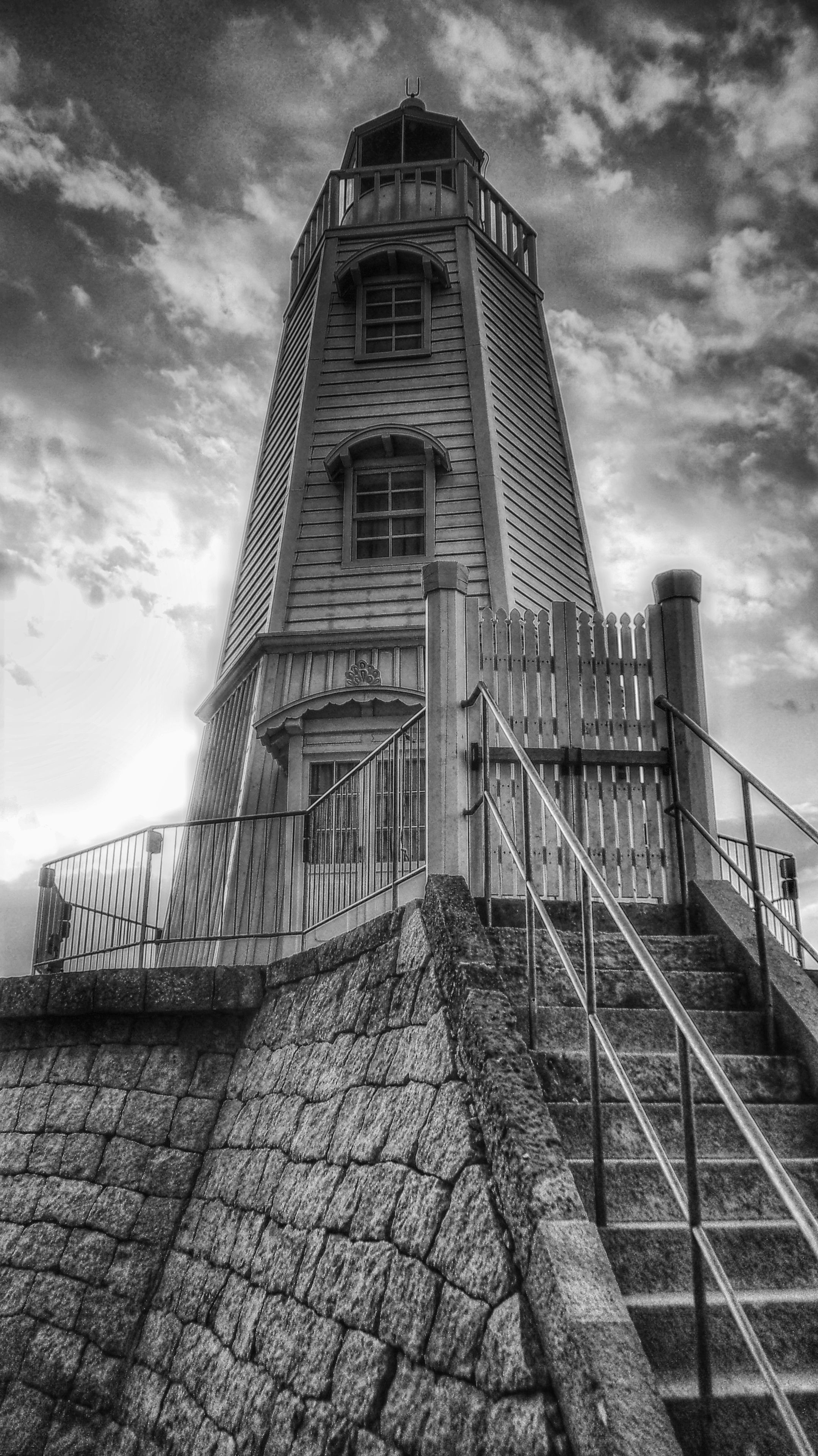A tall, narrow tower with a staircase leading up to a gated entrance.