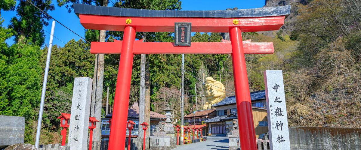 A traditional Japanese torii gate with red pillars and a stone plaque.