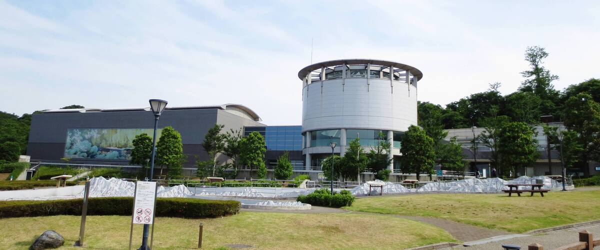 A modern building with a cylindrical section, surrounded by a landscaped area with benches and pathways.