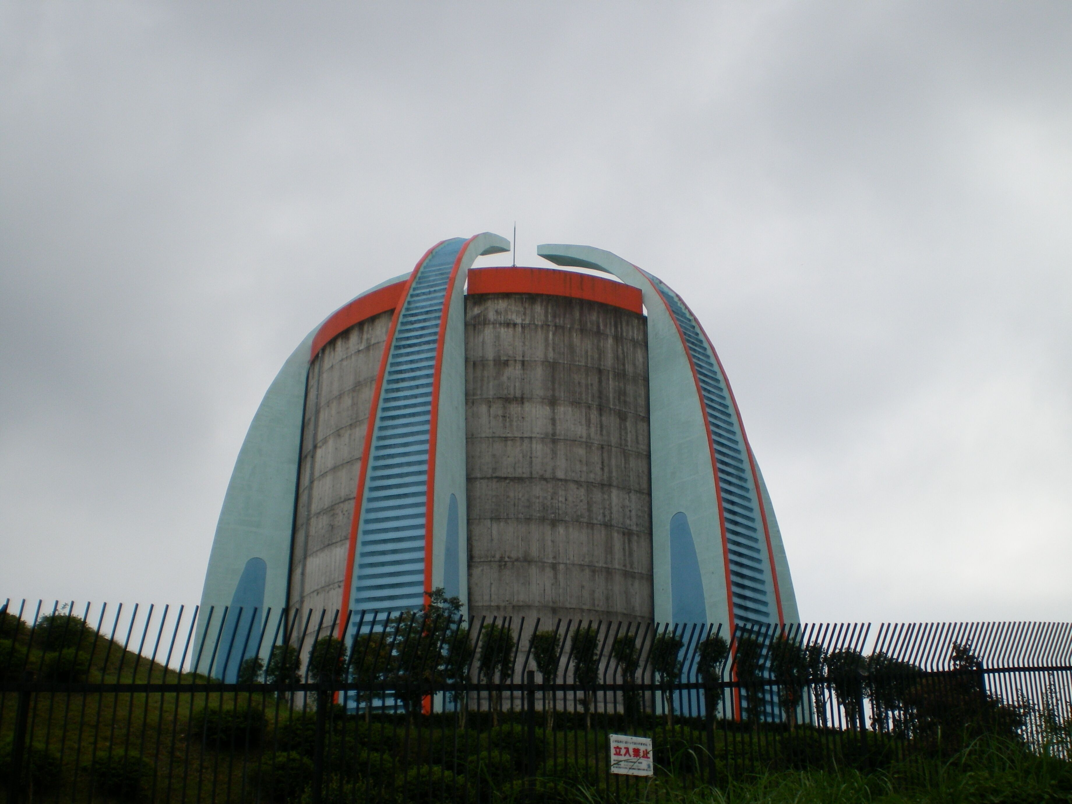 A large, cylindrical building with a curved top, featuring blue and red stripes.