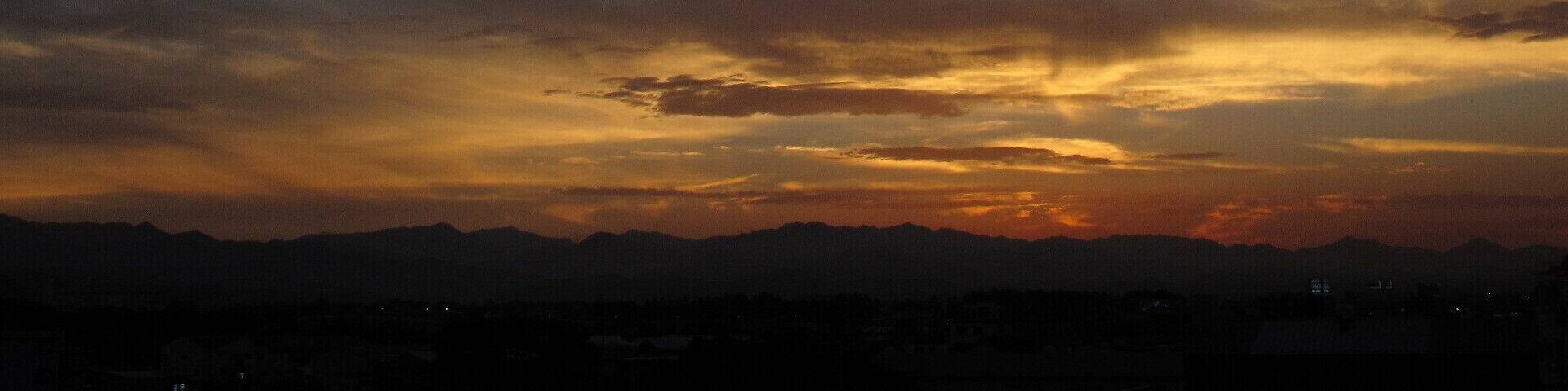 A sunset over a mountain range with a city in the foreground.