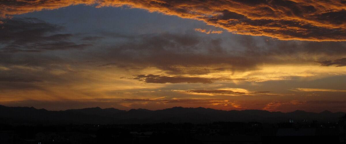 A sunset over a mountain range with a city in the foreground.