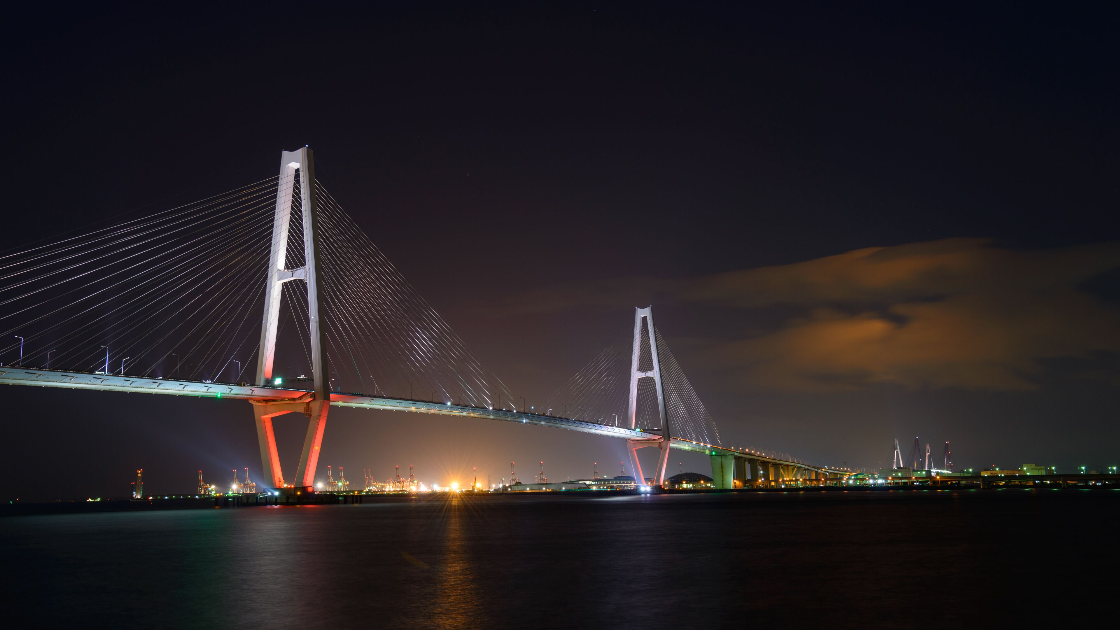 A large cable-stayed bridge at night with illuminated cables and towers.