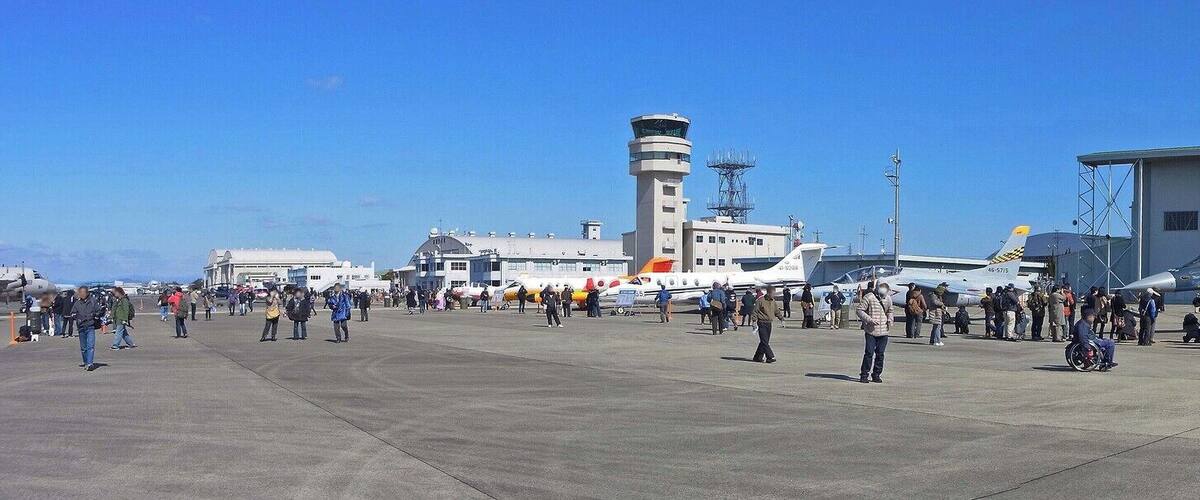 A large hangar, a fighter jet, and a control tower at an airfield.
