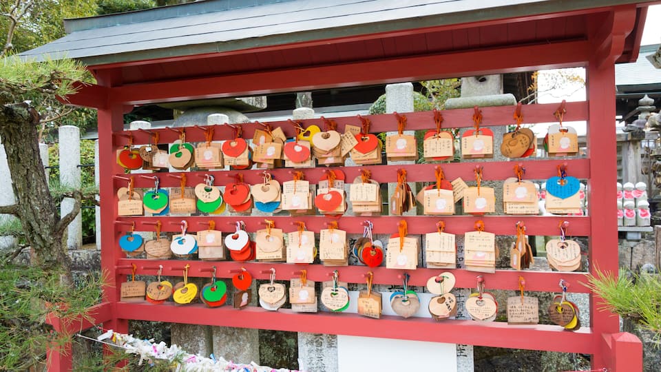 A red shrine with wooden plaques hanging on a shelf.