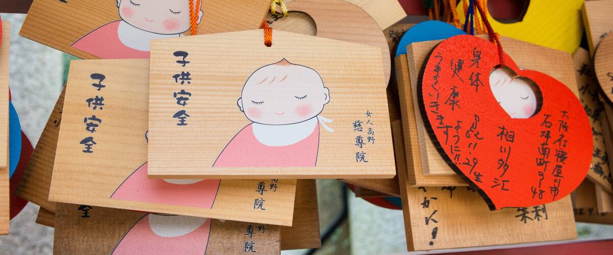 Wooden tags with Japanese characters and a heart-shaped tag with a doll.