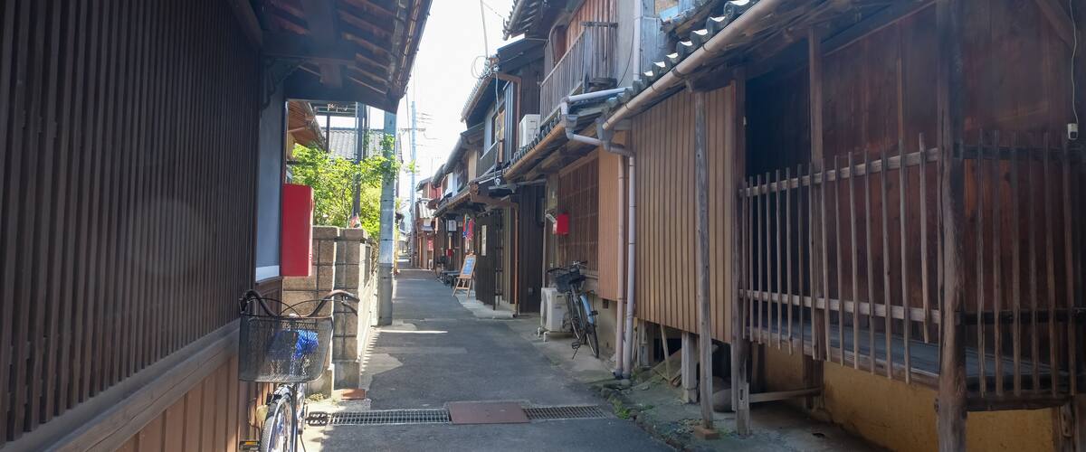 A narrow street flanked by traditional wooden buildings with tiled roofs and a bicycle parked on the left.