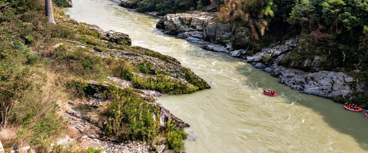A river with rapids, surrounded by lush greenery and rocky terrain.