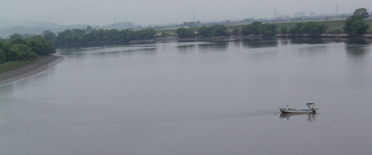 A calm river with a small boat anchored in the middle.