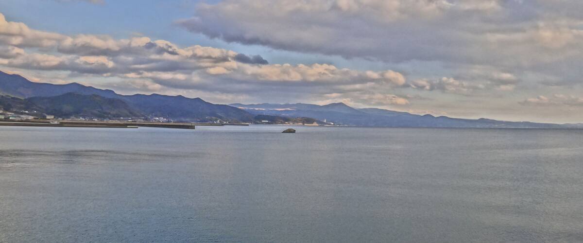 A calm sea with mountains in the background and a clear sky.