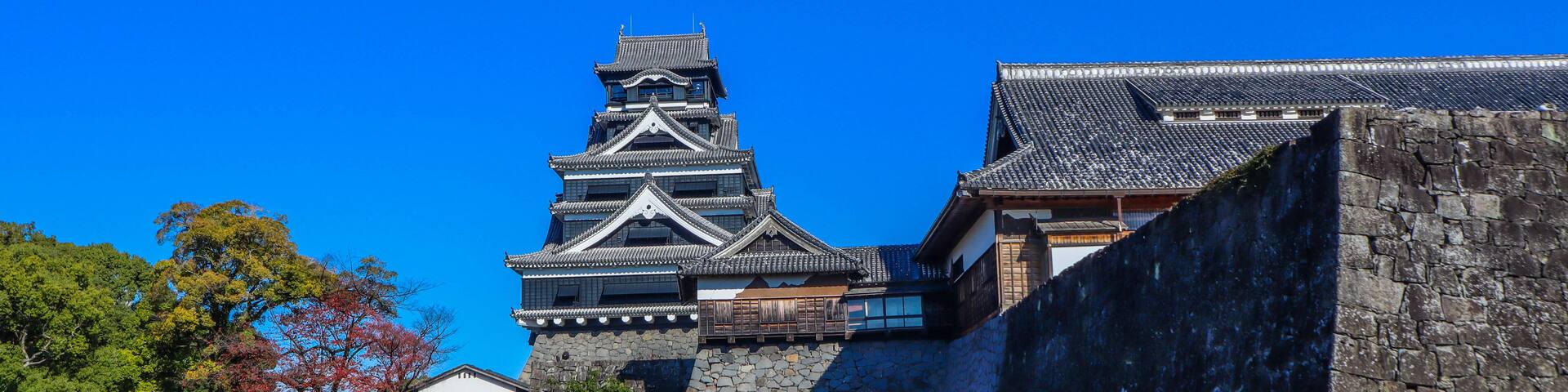 A traditional Japanese castle with multiple tiers and a stone wall.