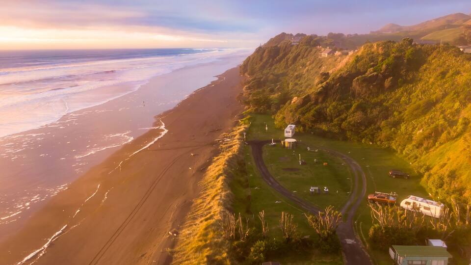 A coastal landscape with a beach, a winding road, and scattered buildings.