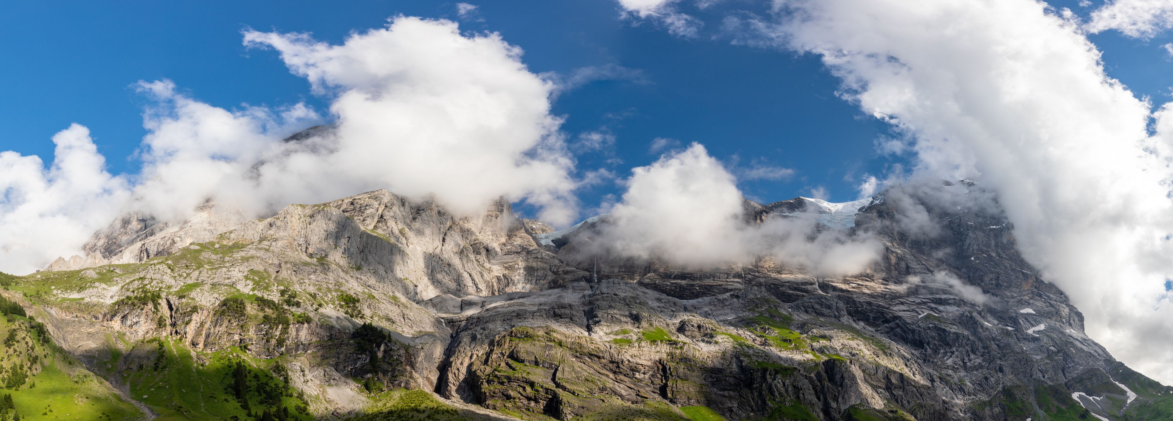 A rugged mountain landscape with a clear blue sky and clouds.