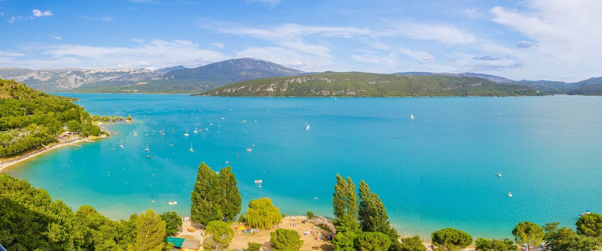 A turquoise lake surrounded by green hills and mountains.