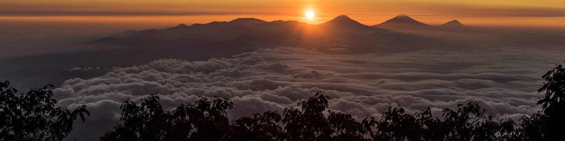 Wonderful remarkable sunrise with sea of clouds below Dieng plateau, Sumbing, Sindoro and Merbabu volcanoes seen from Slamet at 3200 meter above sea level altitude . Central Java, Indonesia