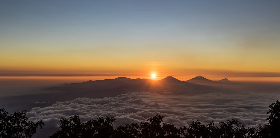 Wonderful remarkable sunrise with sea of clouds below Dieng plateau, Sumbing, Sindoro and Merbabu volcanoes seen from Slamet at 3200 meter above sea level altitude . Central Java, Indonesia