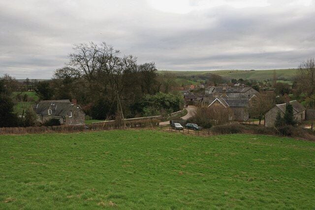 A rural landscape with houses, a field, and a tree.