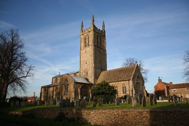A church with a tall tower and a graveyard in front.