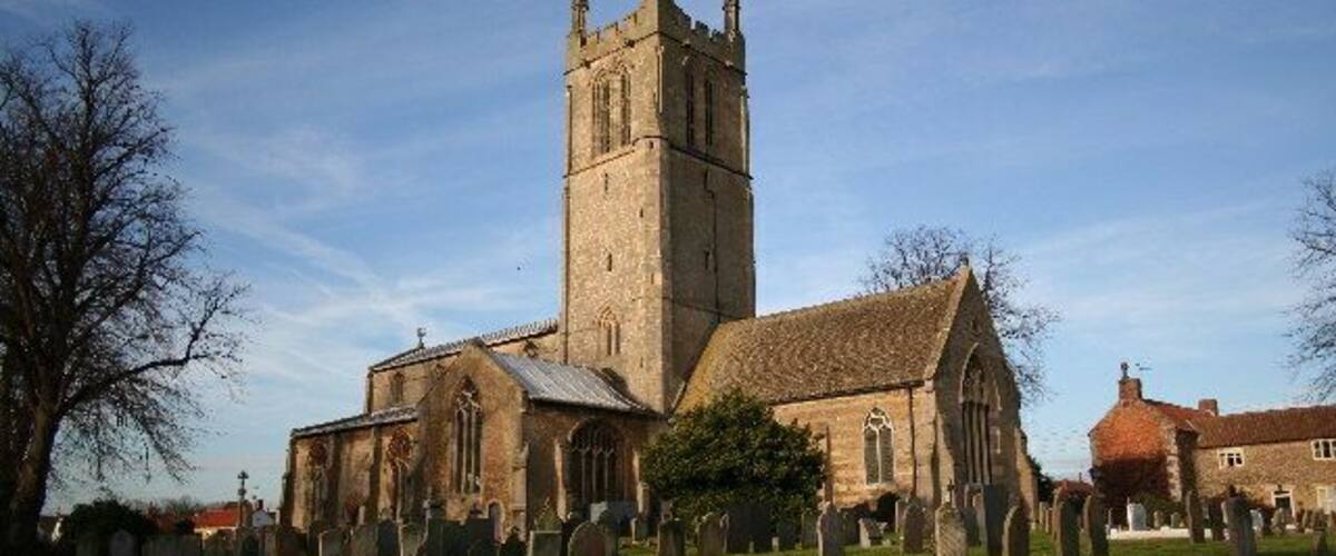 A church with a tall tower and a graveyard in front.