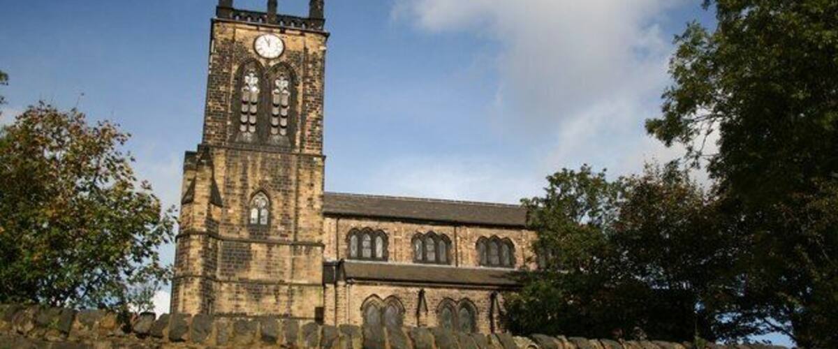 A historic stone church with a tall clock tower and arched windows.