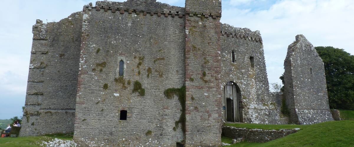 A large, historic stone castle with a tall tower and a partially intact wall.