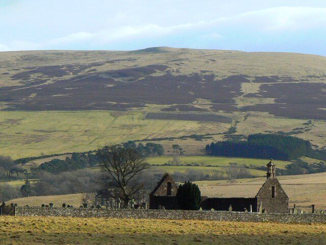 A rural landscape with rolling hills, a stone church, and a stone wall.