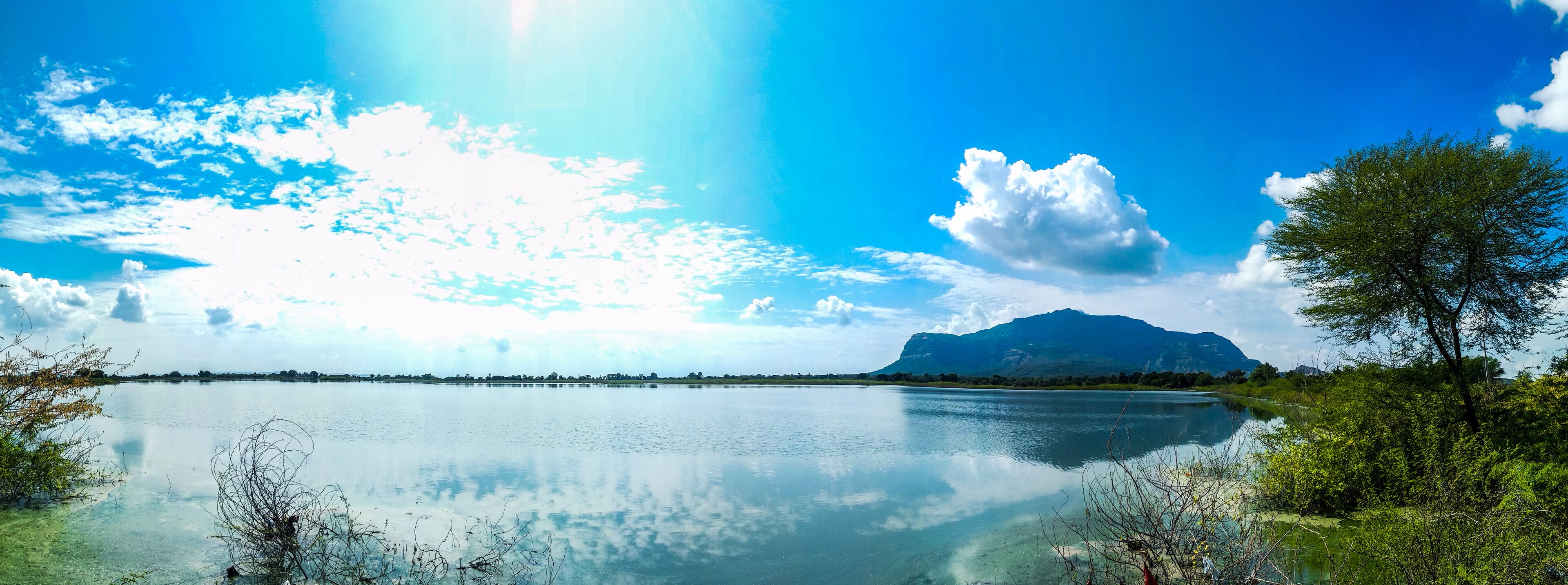 A calm lake with a mountain in the background and a clear blue sky.