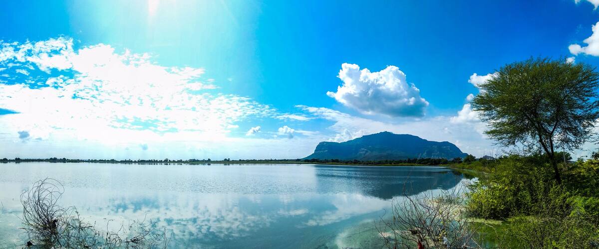 A calm lake with a mountain in the background and a clear blue sky.