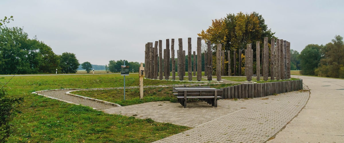 A park with a wooden structure, a paved walkway, and a bench.