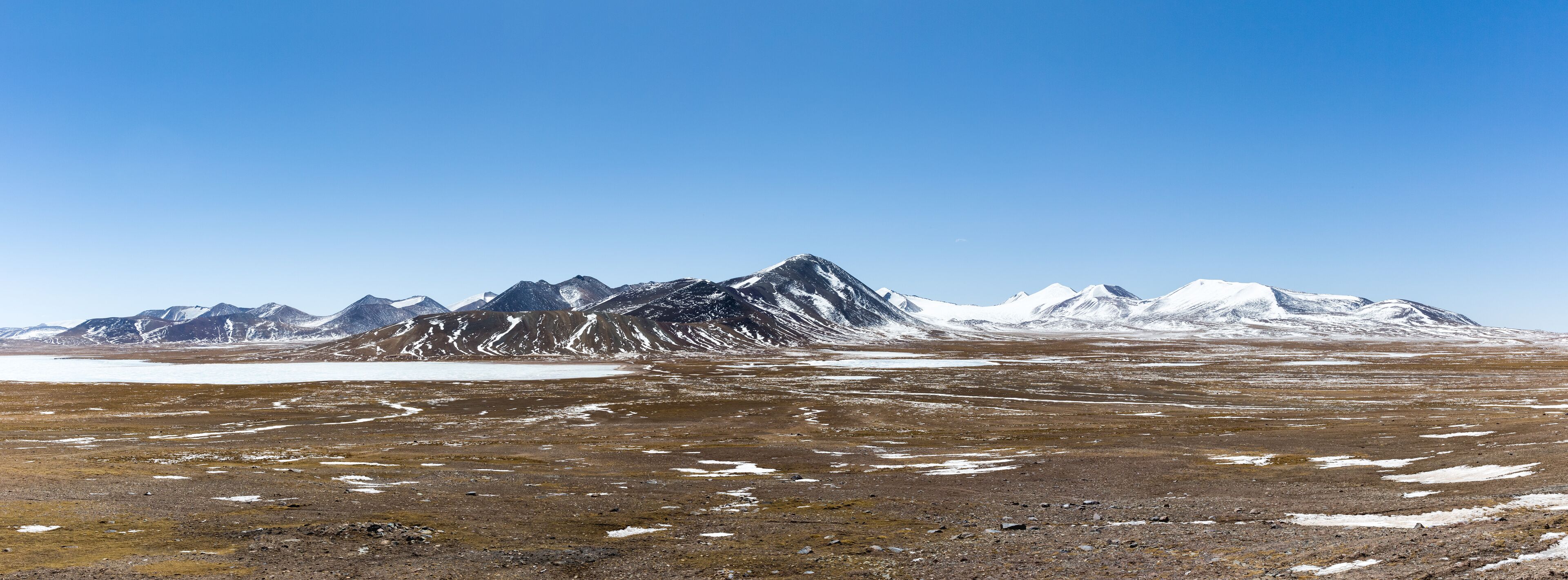 A mountainous landscape with snow-capped peaks and a barren terrain.