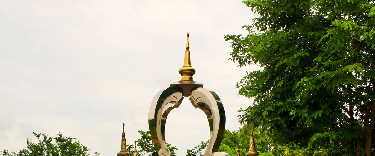 A large, ornate monument with a golden spire, surrounded by lush greenery.
