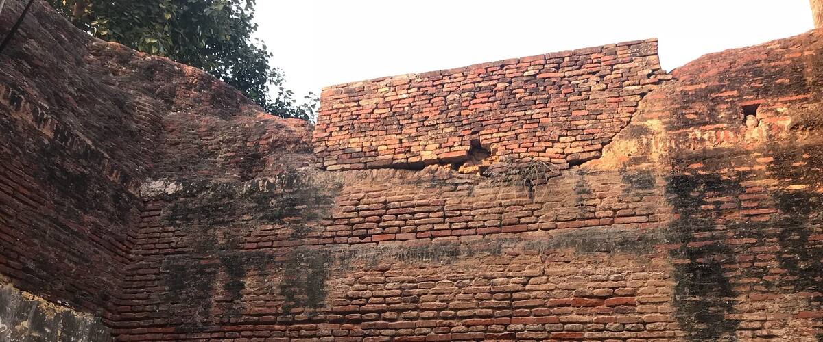 A brick wall with graffiti and two posters of deities.