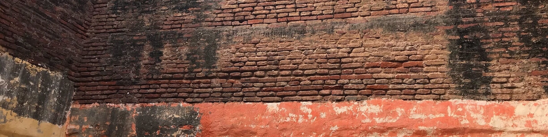 A brick wall with graffiti and two posters of deities.