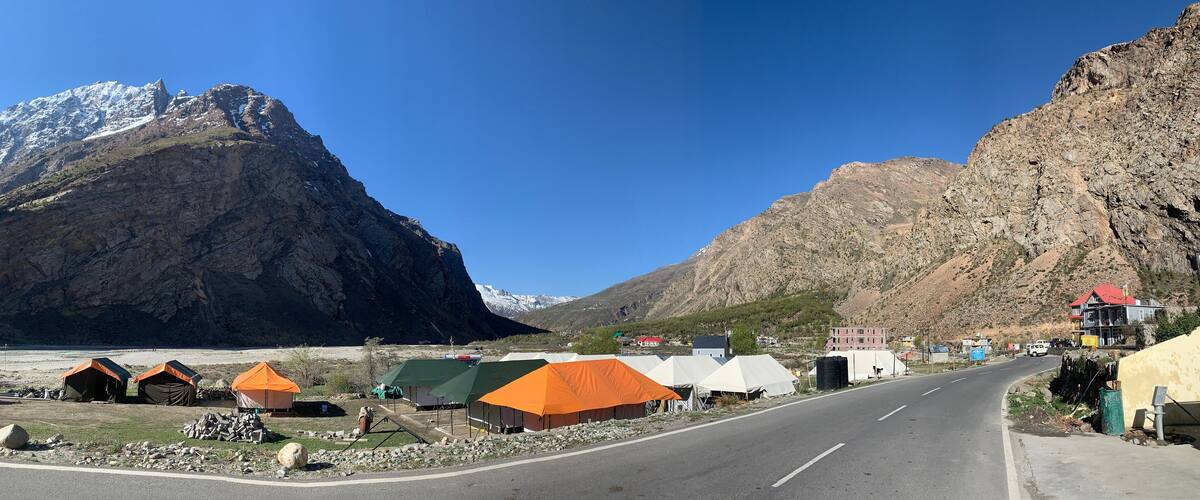 A road with tents and a building in a mountainous area.