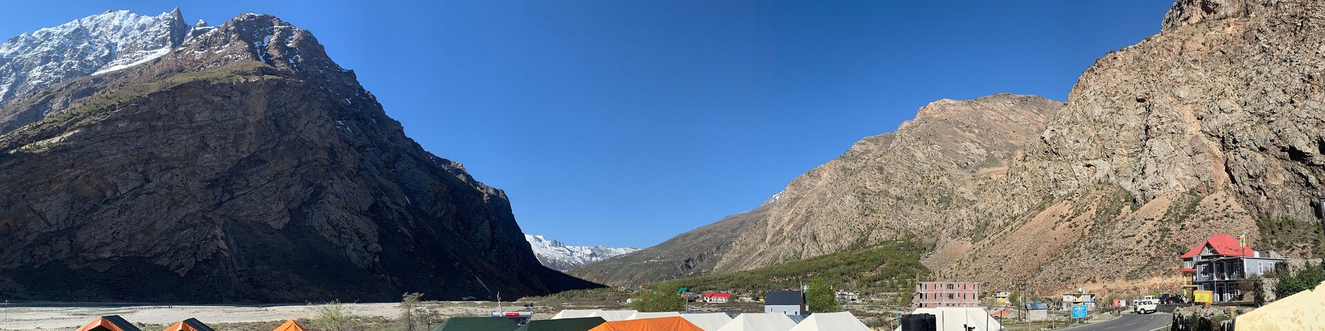 A road with tents and a building in a mountainous area.