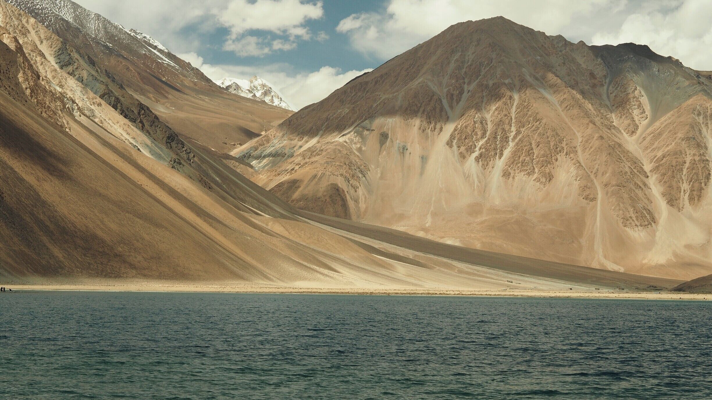 A mountainous landscape with a body of water in the foreground.