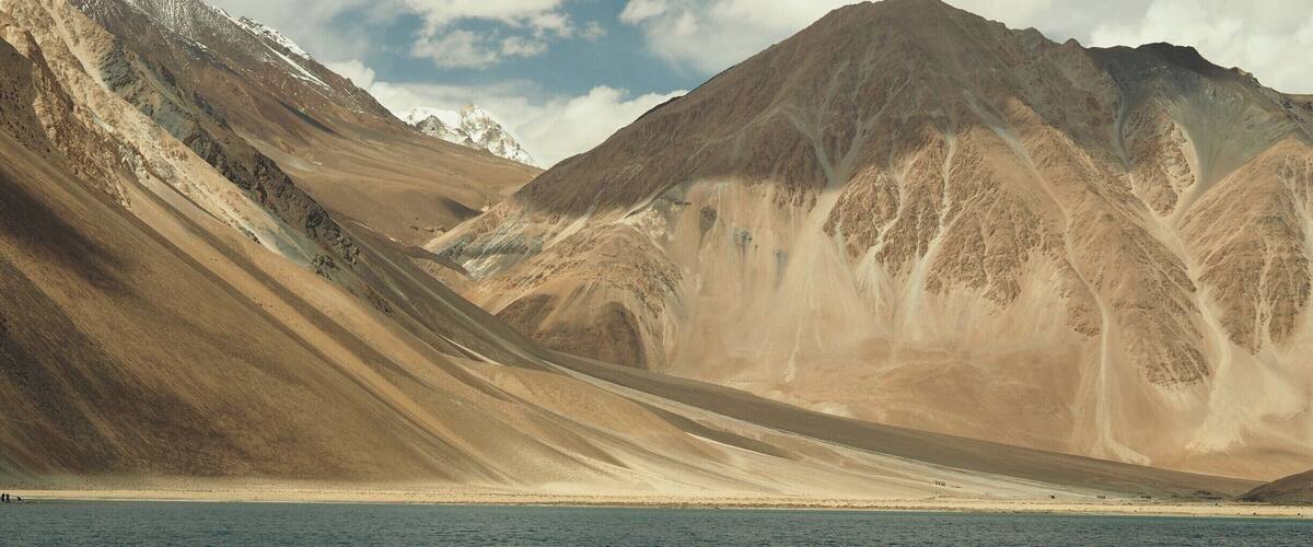 A mountainous landscape with a body of water in the foreground.