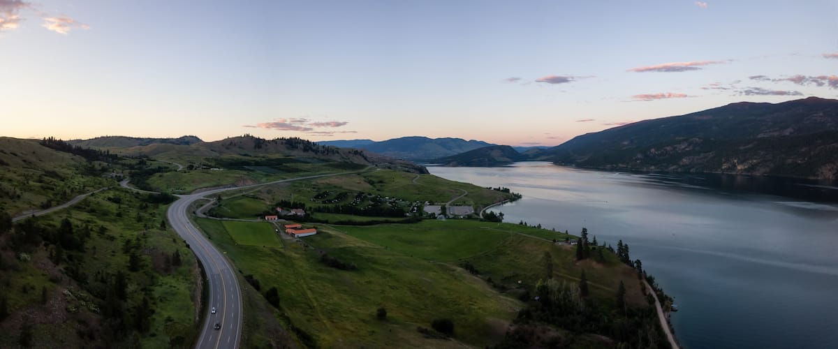 Aerial panoramic view of a highway near Kalamalka Lake during a vibrant summer sunset. Located between Kelowna and Vernon, BC, Canada.