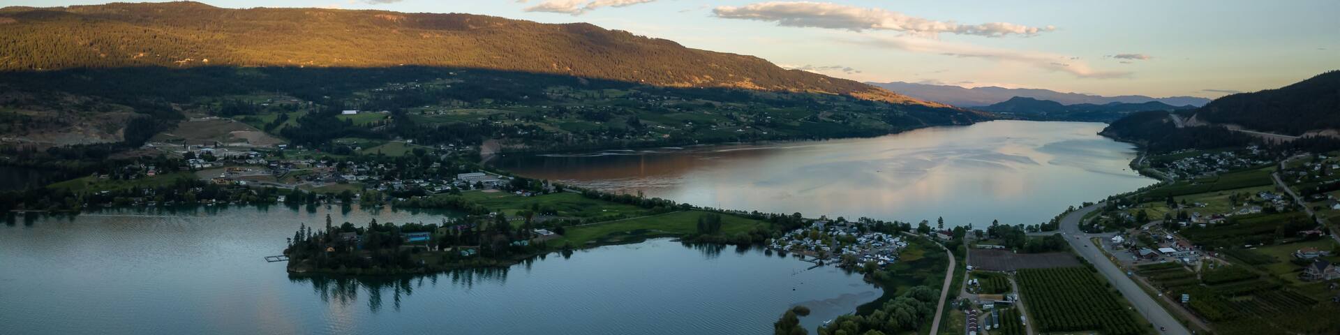 A lake surrounded by mountains, a small town, and fields.