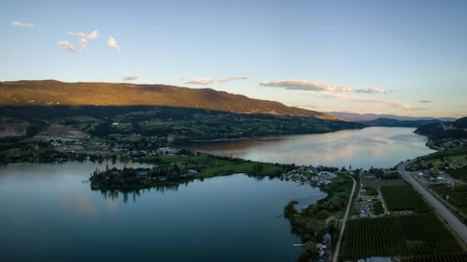 A lake surrounded by mountains, a small town, and fields.