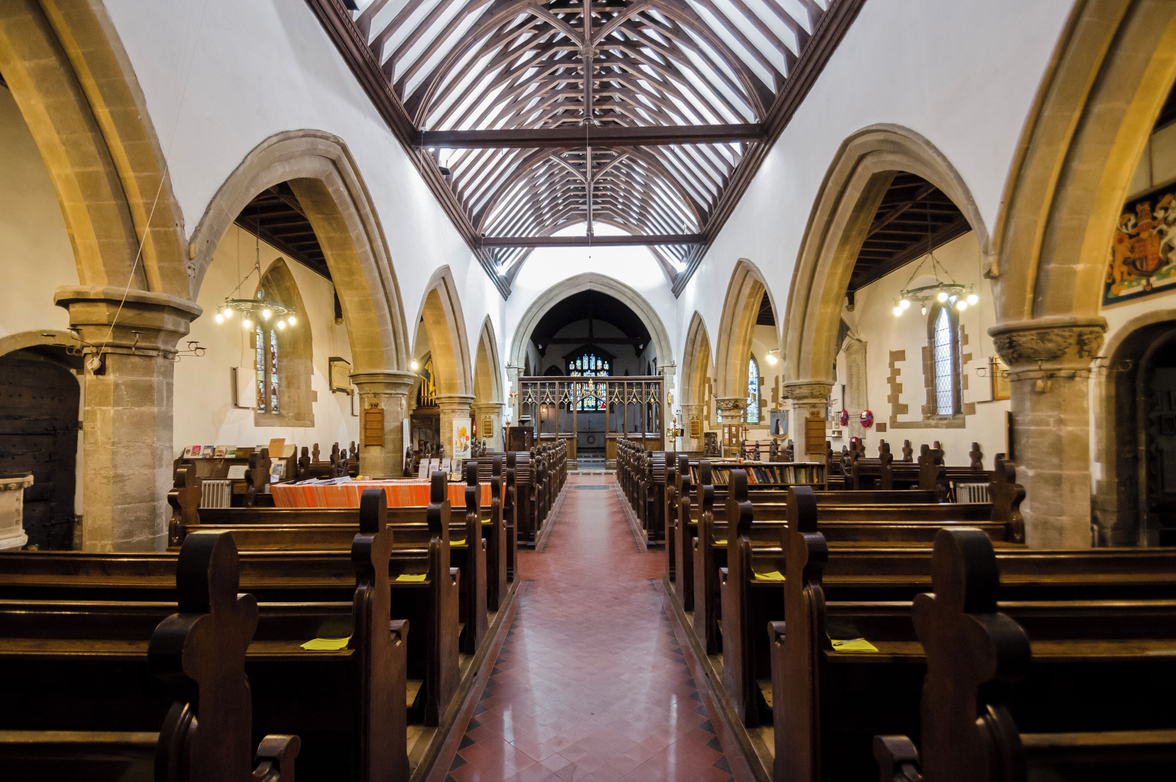 An interior of a church with wooden pews, arched ceilings, and stained glass windows.