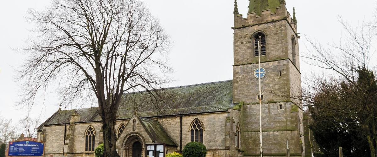 Balderton dates back to Saxon times, and it is known that Lady Godiver the wife of Earl Leofric had property nearby. In the past the Great North Road from London to York passed through the village. There is no trace of an original Saxon church, although one probably existed. The church dates from the 12th century when a simple building, some of which still remains in the nave, was constructed. The north and south doorways still retain Norman arches with zigzag patterning (although both have been moved from their original position). The church consists of a tower with spire, nave with north and south aisles, north and south porches, and a chancel with north Chapel which houses the organ. The tower dates from the 13th century and is of three stages. It was encased in ashlar in the 1880s. The top is embattled with pinnacles and gargoyles. The spire dates from circa 1400 and is crocketted with lucarnes. There are 8 bells. The nave has four bay arcades with octagonal piers. In the 13th century the north aisle was added and a larger chancel was built. Shortly after, the nave was extended westward, and the building of the tower commenced, this was delayed by the Black Death of 1347. The south aisle was added in the 14th century. The font also dates from this time. It is octagonal, with ball flower ornamentation. Around this time a clerestory was added, which was later removed in Victorian times. The screen dates from the 15th century and it was originally brightly painted and had panels of Biblical scenes. Evidence of the stonework supporting the rood loft was removed during restoration in 1882. In the late 15th century the pews were installed. These have carved poppy heads depicting animals and other figures, one man is playing Lincolnshire bagpipes. There are also undecorated 19th-century pews. The pulpit is from around 1475 and was previously on the south side of the chancel arch but was moved in 1882. The north door with its wicket is of the same 15th century period. The Victorian restoration of the church took place in 1882, when the nave roof was altered and the clerestory removed. The chancel roof had already been replaced in 1850, and additional pews were installed. The north porch was rebuilt incorporating the Norman arch. In 1929 cracks were found in the tower wall and major repairs to the foundations were undertaken. A new vestry was constructed in 1964 on the south side of the church. In 1983 the chancel was encased in Ancaster stone, matching the rest of the church. There are several 19th-century stained-glass windows and some reset fragments of 15th century glass which were found in the churchyard.