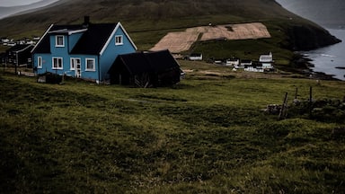 A blue house, a mountain, and a body of water.