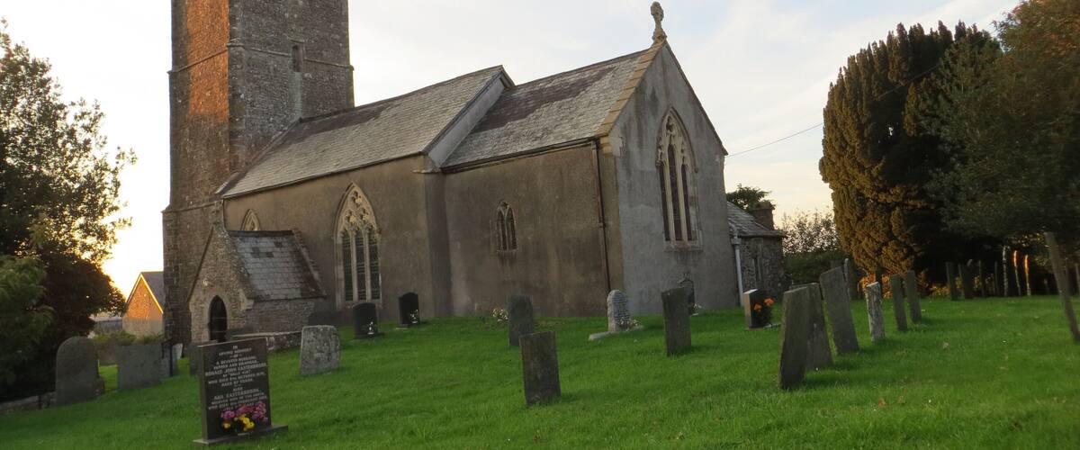 A church with a tall tower and a graveyard in front.